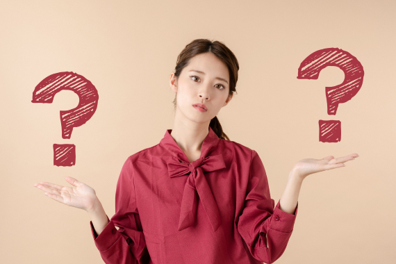 赤いブラウス姿で両手を広げ、左右に大きな疑問符を示している女性